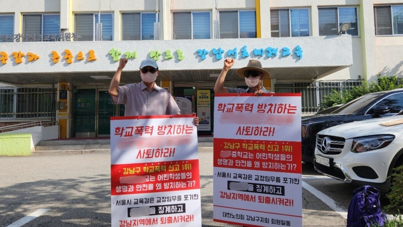 강남교육청앞에서 피해학생 보호자가 피켓을들고 시위를 하고있다.