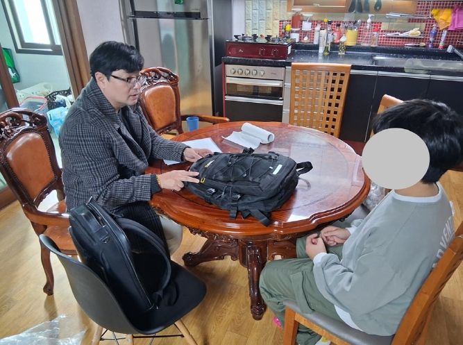 신안군 드림스타트 아동통합사례관리사가 가정 방문하여 아동에게 책가방을 전달하고 있다.