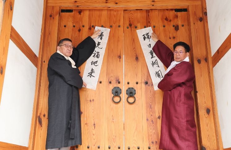 박강수 마포구청장(오른쪽)이 2026년 2월 4일 오전 광흥당 대문에 입춘축을 붙이고 있다.