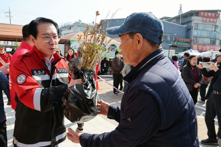 송인헌 괴산군수가 23일 괴산시장 다목적광장에서 방문객에게 묘목을 나누어 주고 있다.